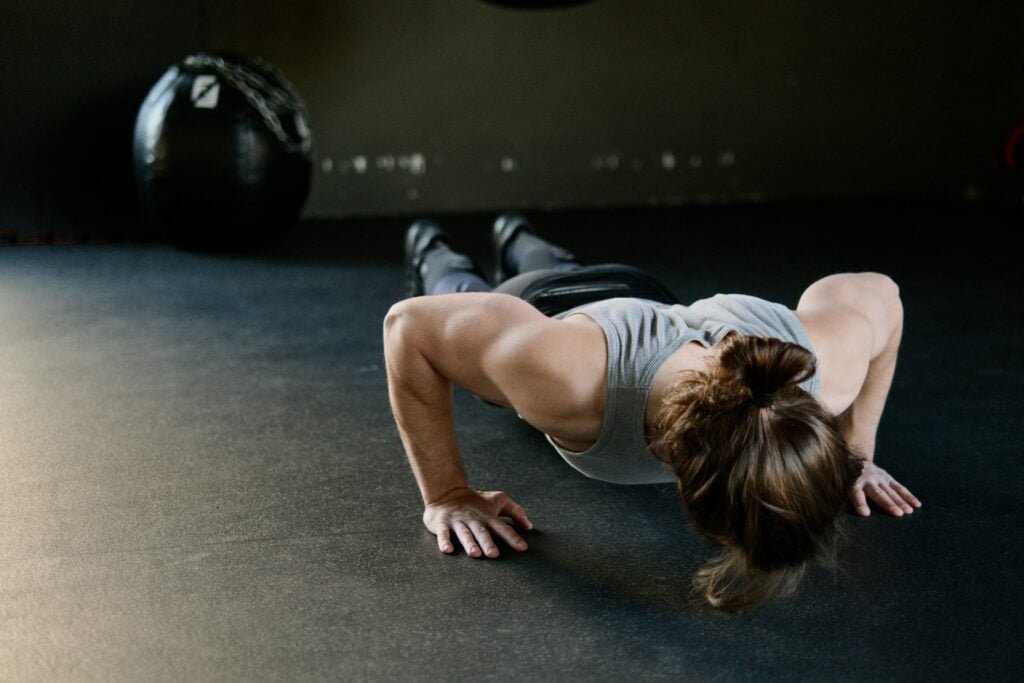 Person demonstrating a push-up in a living room setting as part of an at-home workout routine